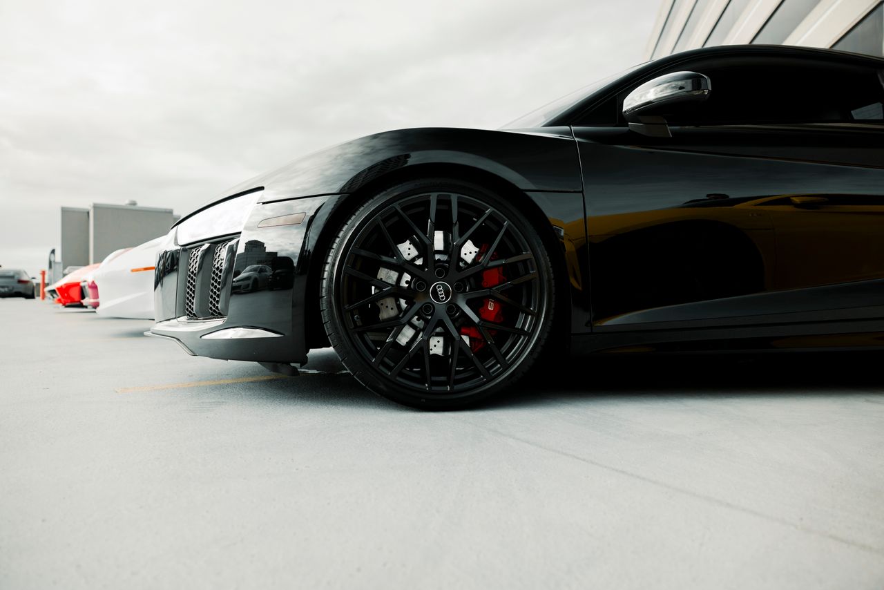 Close-up of a black luxury sports cars wheel detail in an outdoor setting.